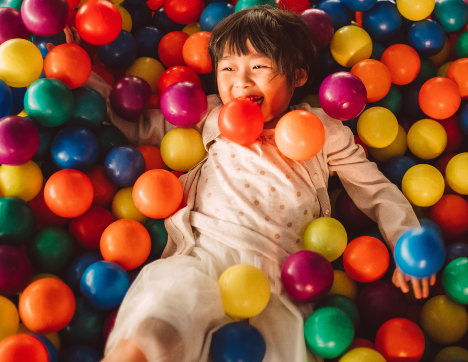 Child lying in a colourful ball pit