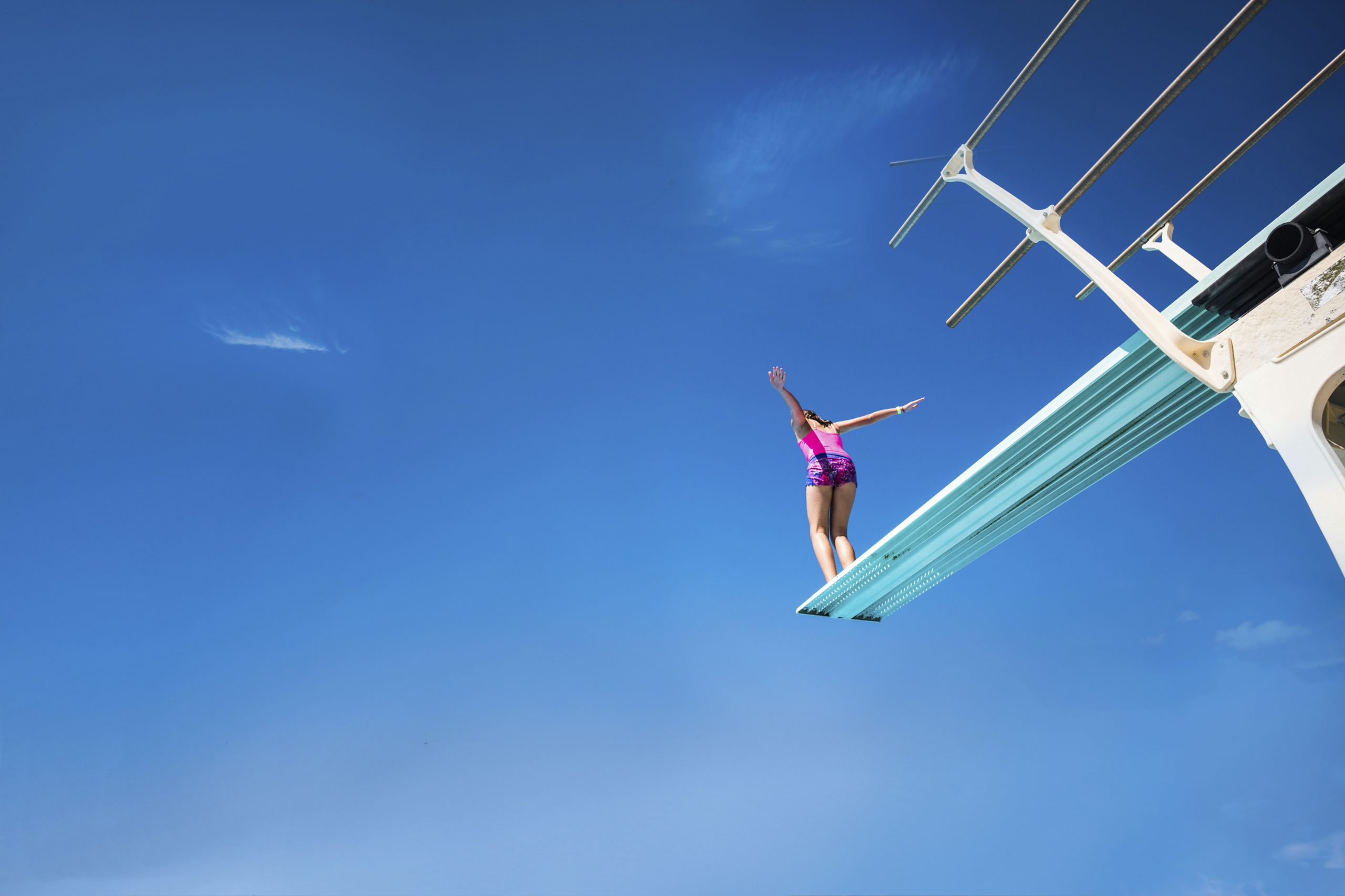 Child about to jump off a diving board - clear skies