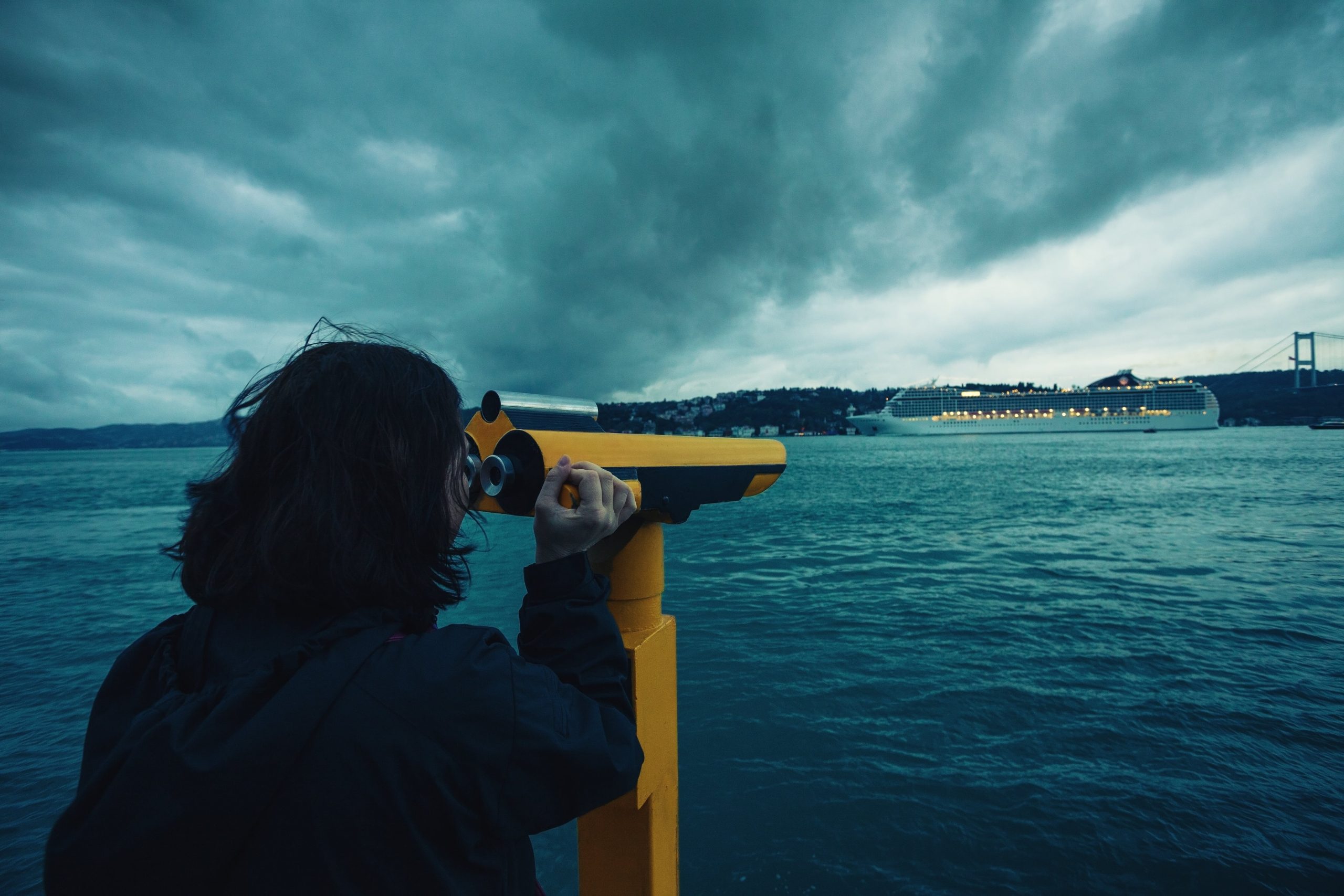 Female looking through a telescope out to sea