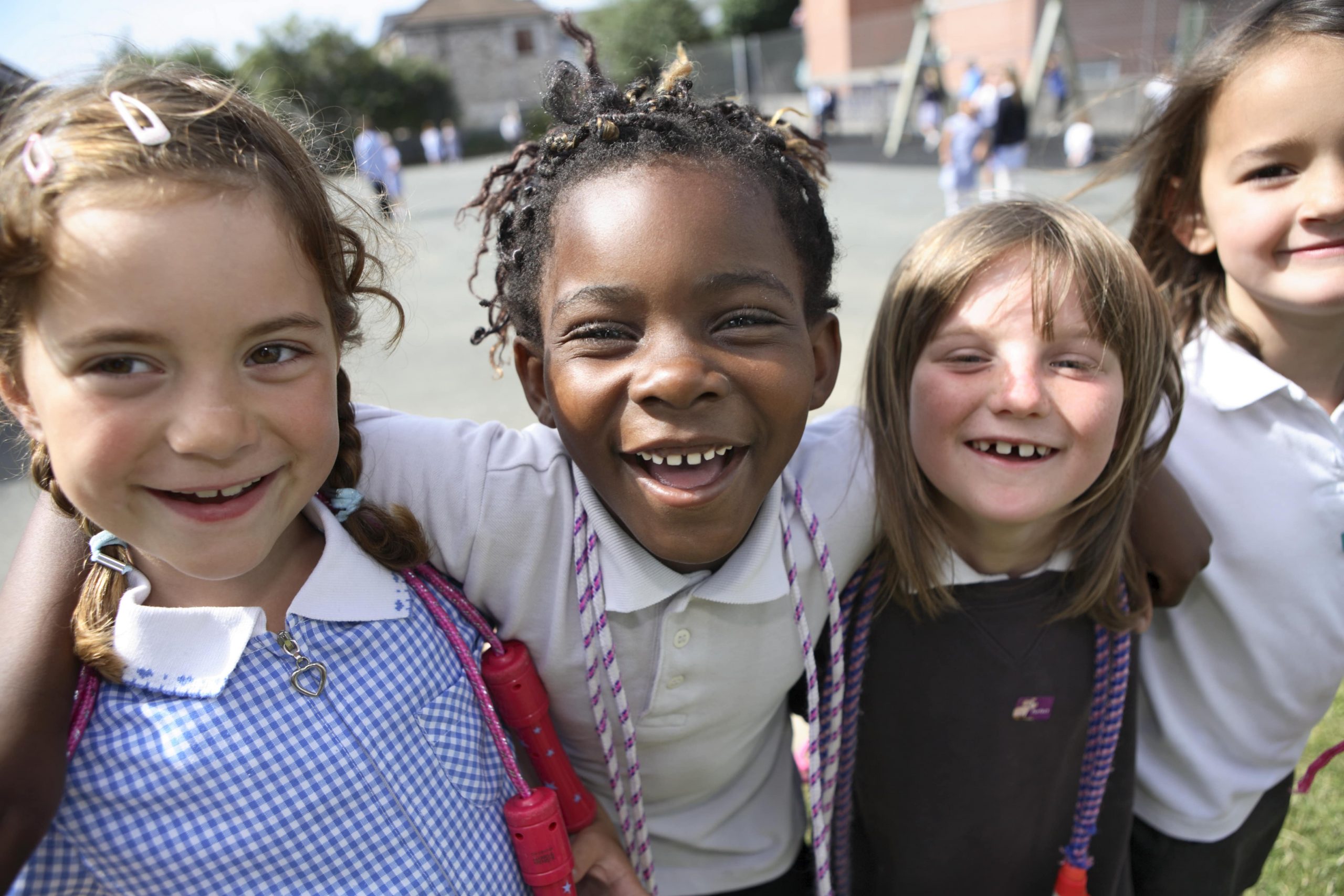 4 smiling kids in school playground